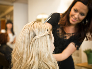 Instructor at The Forum Academy teaching hair style techniques to students on a model.